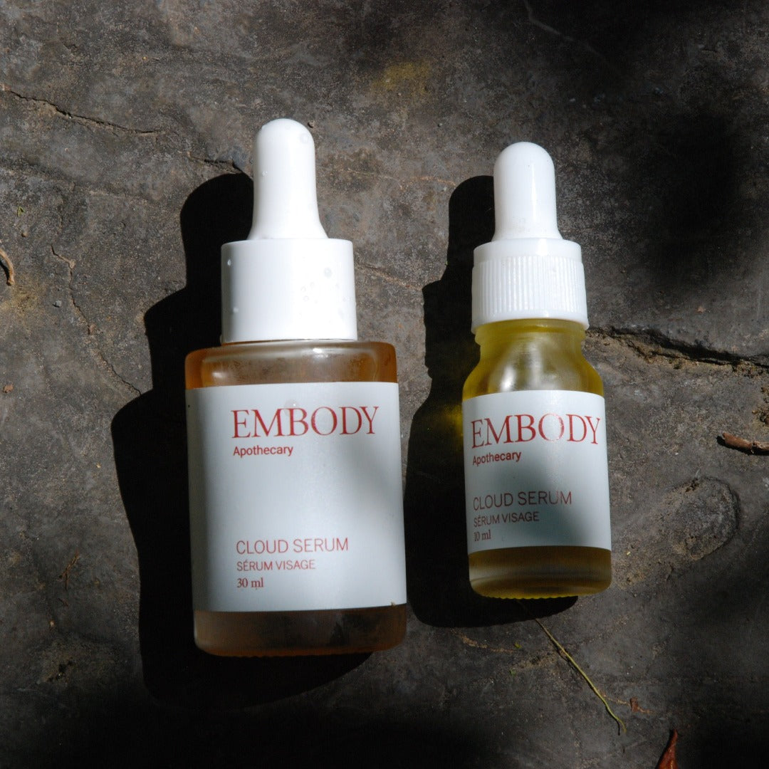 A Regular and Travel Sized Cloud Serum sit side by side. The vibrant orange, yellow, and green colours of the facial serums showing off the 100% local Canadian ingredients they&#39;re made from.