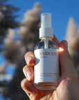The Handcrafted hydrosol based Earth to Sky Facial Toner is being held up to the blue sky