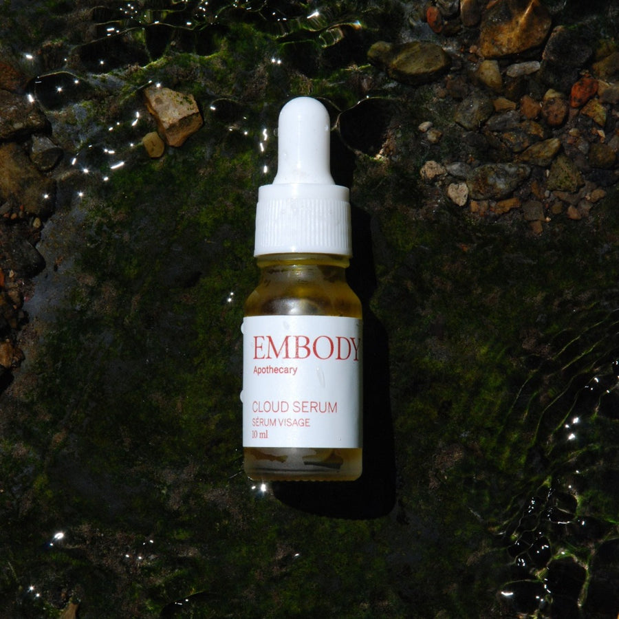 Travel size 10ml Cloud Serum, handcrafted in Montreal using sustainable Canadian ingredients, sits in a river near Quebec.