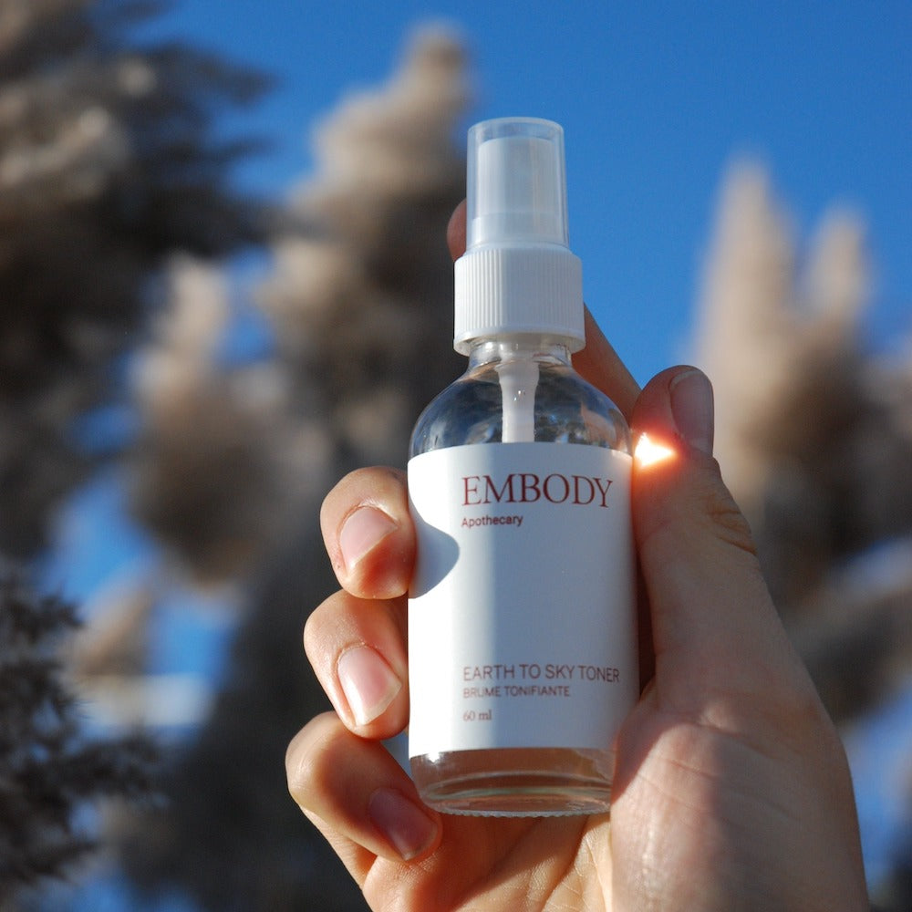 The Handcrafted hydrosol based Earth to Sky Facial Toner is being held up to the blue sky