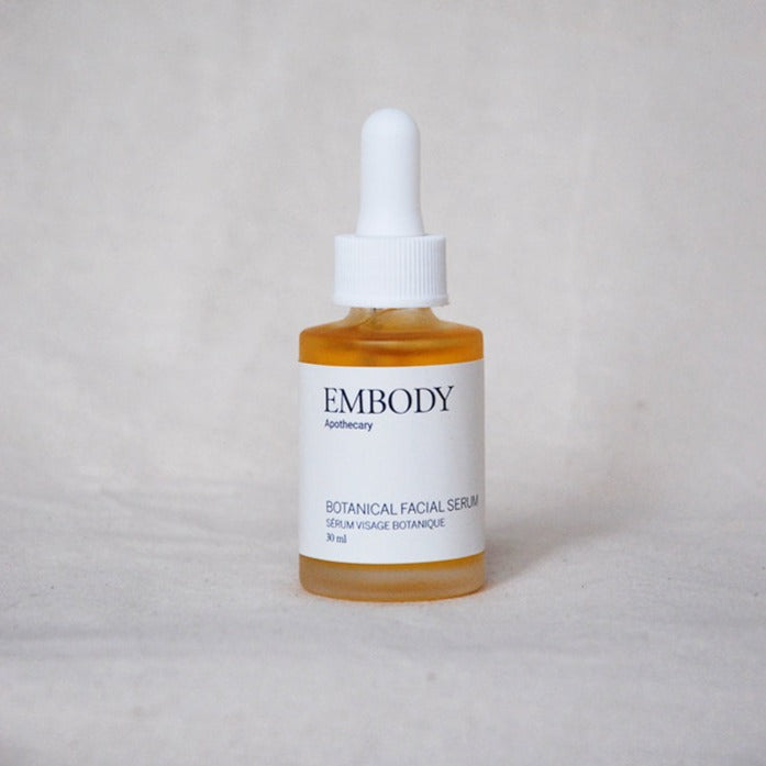 The Botanical Facial Serum sits on display, its golden colour highlighted by a beige backdrop.