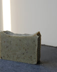 The cold-processed soap bar, Cedarwood and Sage sits in the sunshine on a display.