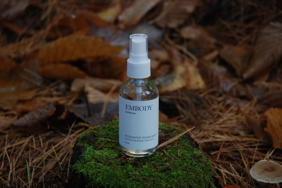 The handcrafted, all natural Rosewater Facial Toning Mist, made with pure Rose hydrosol, sits on a bed of moss in a forest.