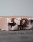 The Sunset Spice soap bar lays on it's side, exposing it raw and natural edges.