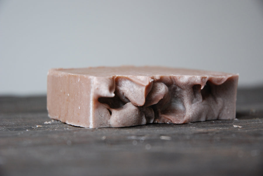 The Sunset Spice soap bar lays on it's side, exposing it raw and natural edges.