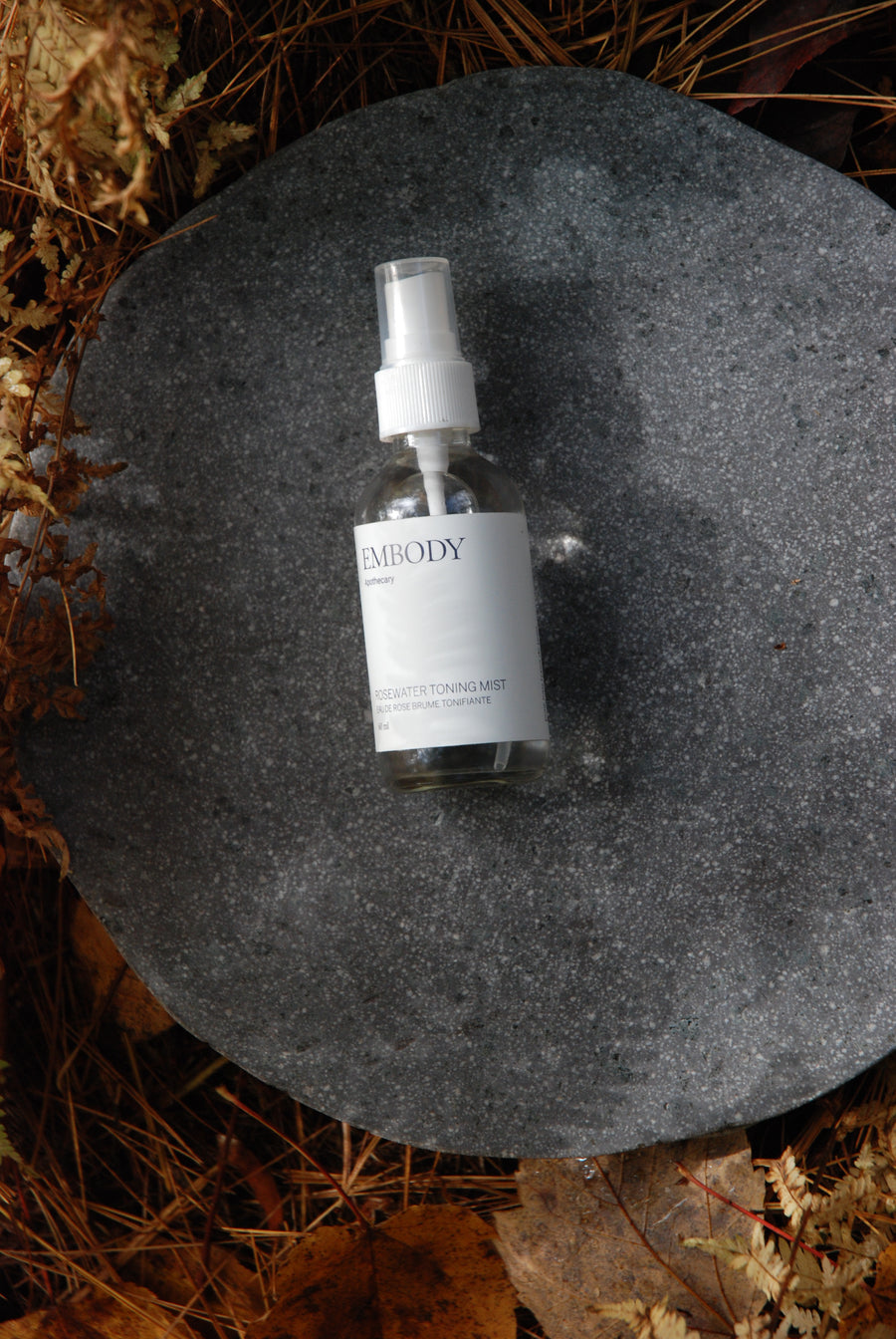 The handcrafted, all natural Rosewater Facial Toning Mist, made with pure Rose hydrosol, sits in a forest.