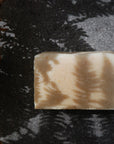 The Sensitive Skin Healing Honey soap bar sits in the shadows of a fern.