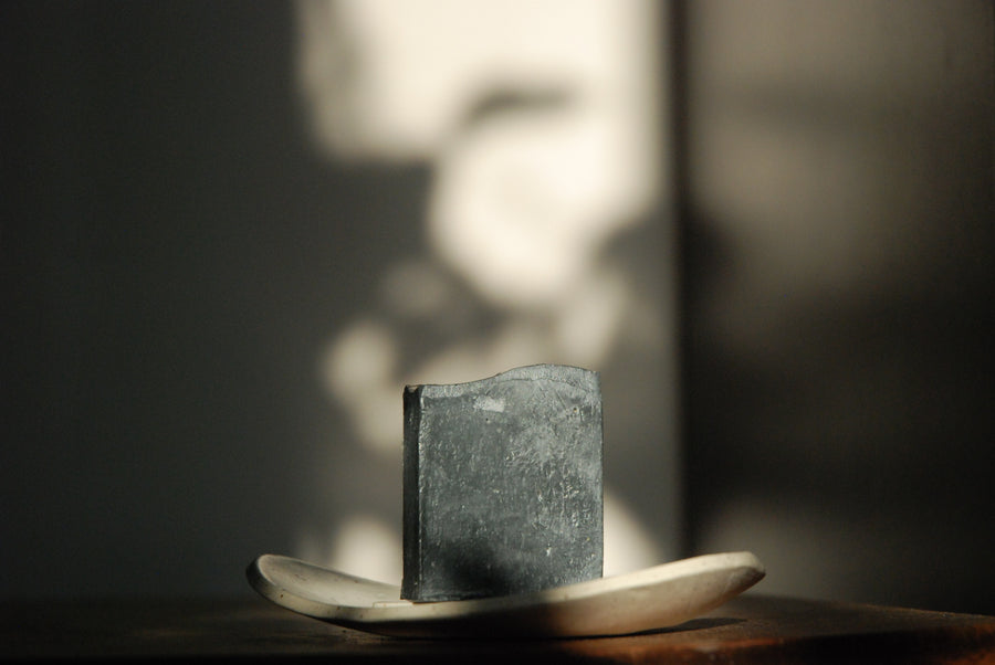 The all-natural and lightly exfoliating Activated Charcoal Facial Soap sits in the sunshine.